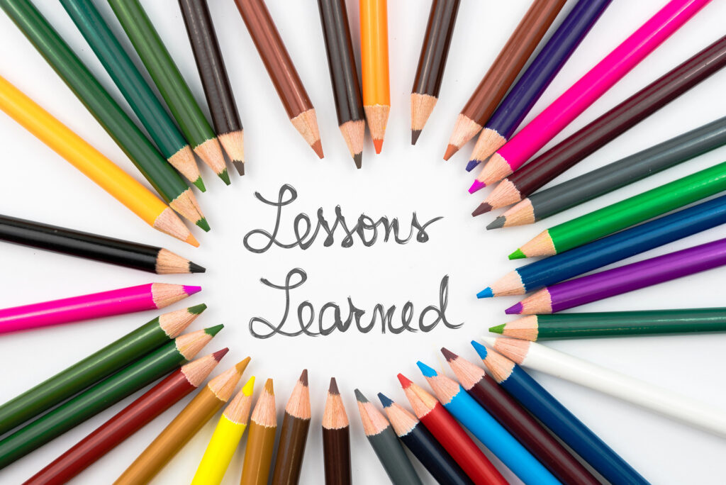 Colorful pencils arranged in a circle around the handwritten words "Lessons Learned"